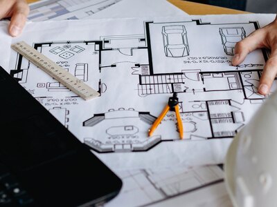 table filled with floor plans, laptop and other engineering things