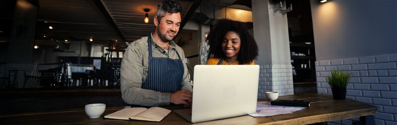 Coffee shop ownerss reviewing analytics data on a laptop