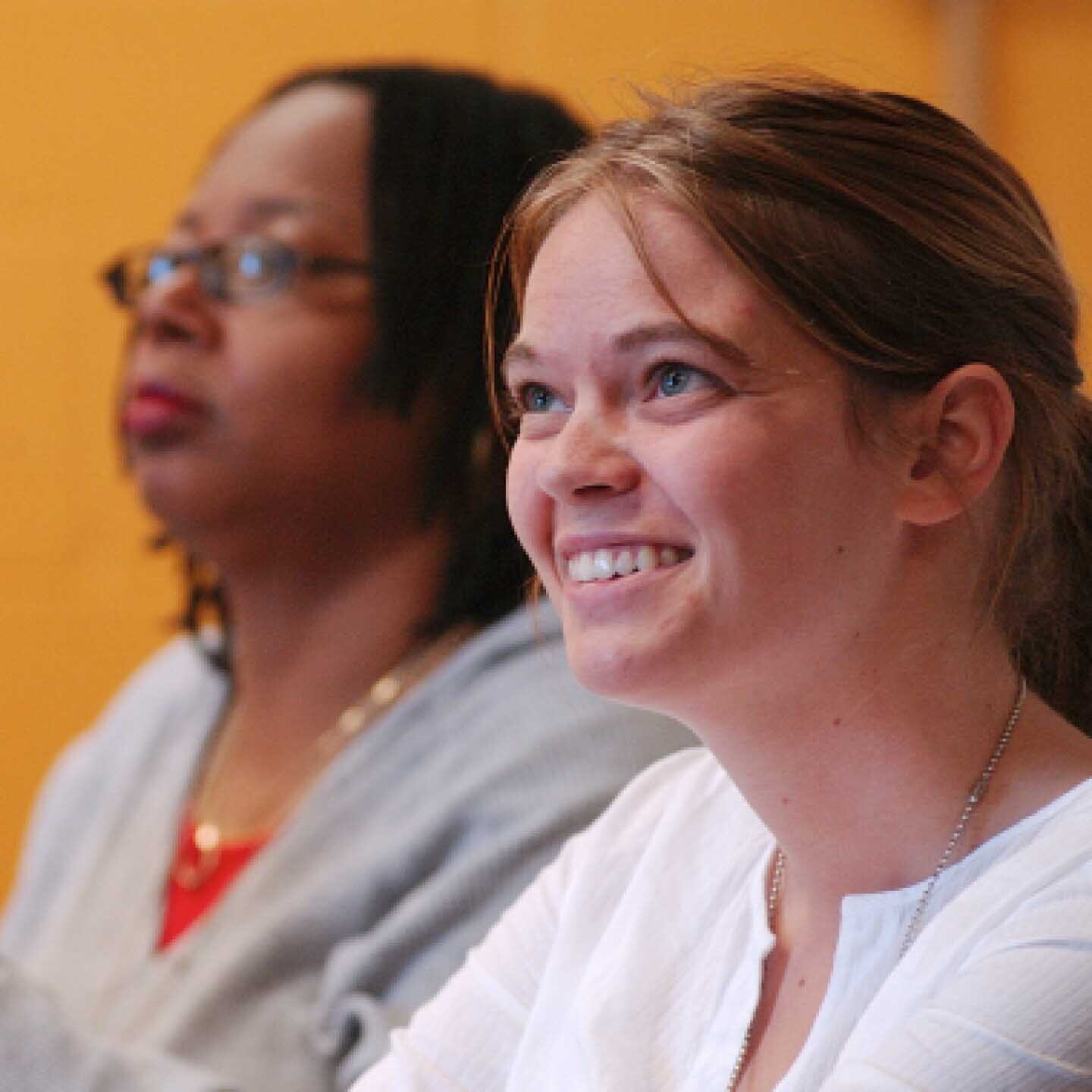 Close-up of two female Yeshiva University students listening during a classroom lecture.