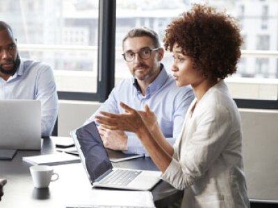 Woman speaking to team around conference table