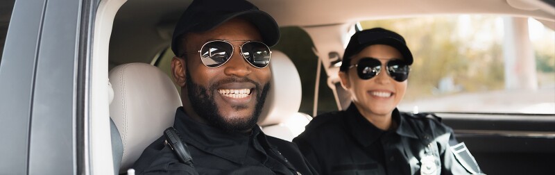 Smiling police officers in a patrol car.