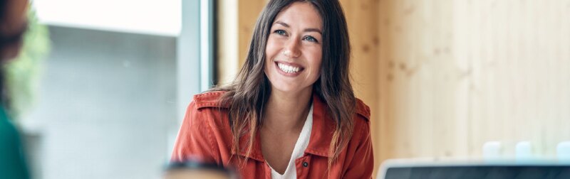 Smiling young business woman listening her partner on coworking space.
