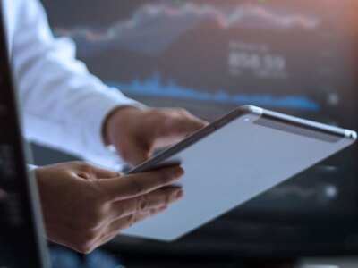 Businessman using tablet for analyzing data in monitoring room with team.