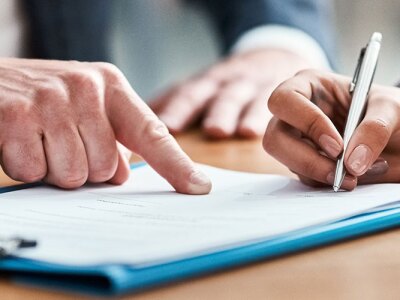 A person signing a document on a conference table
