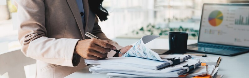 Accountant working on large pile of documents at her desk.